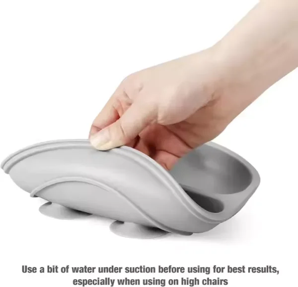 Gray silicone suction bowl being lifted to show strong grip and flexibility for baby feeding