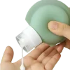 Squeezable silicone travel bottle dispensing lotion into hand, ideal for toiletries and airport-friendly containers