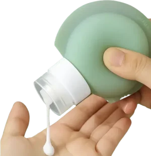 Squeezable silicone travel bottle dispensing lotion into hand, ideal for toiletries and airport-friendly containers