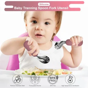 Baby holding training spoon and fork set with soft handles.