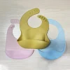 Pink silicone baby bib with adjustable buttons and wide pocket.