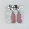 Packaged Baby Spoon and Fork Set Pink-handled baby spoon and fork set sealed in clear plastic packaging.