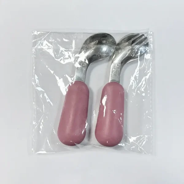 Packaged Baby Utensils – Back View Back view of pink-handled baby spoon and fork set in sealed plastic packaging.