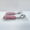 Packaged Baby Utensils – Side View Side view of pink-handled baby spoon and fork set in sealed packaging.