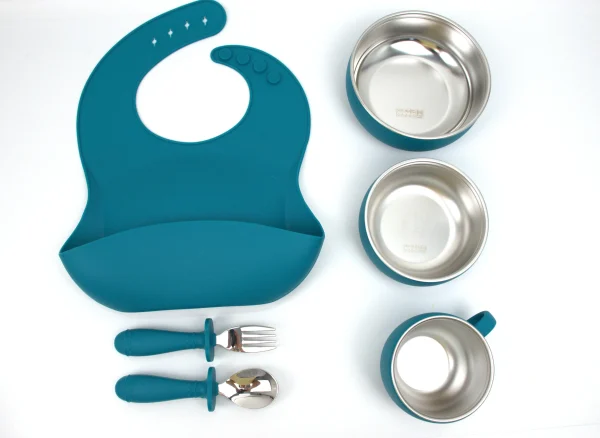 Gray silicone feeding set with stainless steel bowls and baby bib. Gray silicone toddler meal kit with bib, bowls, cup, spoon, and fork.