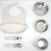 Beige Silicone Baby Meal Kit Beige silicone baby feeding set with bib, bowls, cup, spoon, and fork.